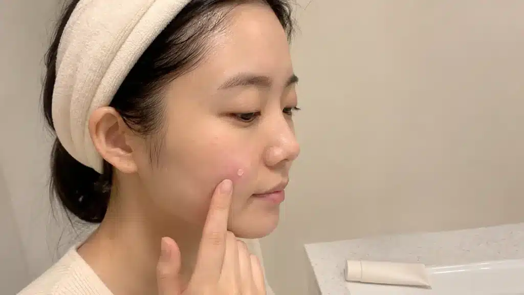 세안 후 붉어진 볼 부위에 보습 크림을 조심스럽게 바르는 여성