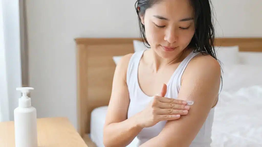 샤워 후 팔의 거친 피부에 보습제를 바르는 여성